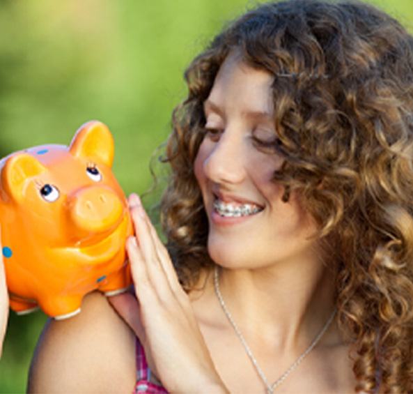 Woman with braces smiling at an orange piggy bank