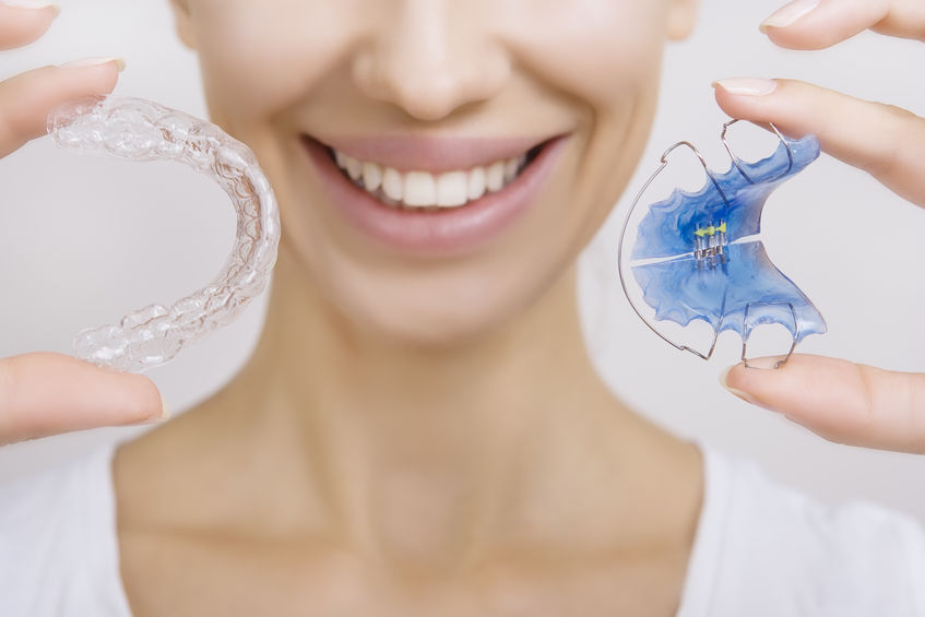 Woman holding clear and traditional retainers