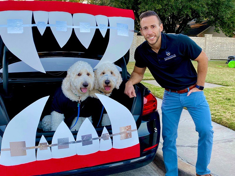 Doctor Buchwald next to car with decorations of fangs with braces and dogs sitting in trunk