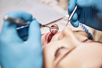 Dentist examining patient's teeth with dental tools