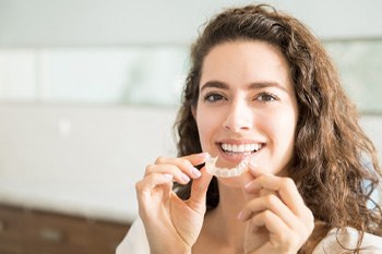 Woman smiling while holding clear aligner