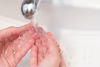 Patient rinsing clear aligners in sink