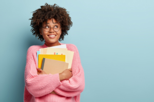 Young woman on blue background holding notebooks